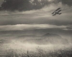 Black and white image of a bi-plane above Edinburgh